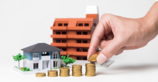 real estate and funds, hand holding a coin